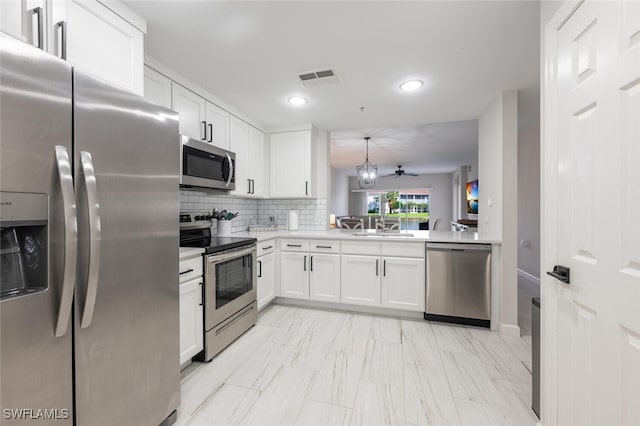 kitchen with decorative backsplash, kitchen peninsula, stainless steel appliances, sink, and white cabinets