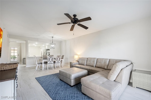 living room with light hardwood / wood-style flooring and ceiling fan with notable chandelier