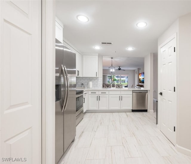 kitchen with hanging light fixtures, kitchen peninsula, stainless steel appliances, white cabinets, and tasteful backsplash