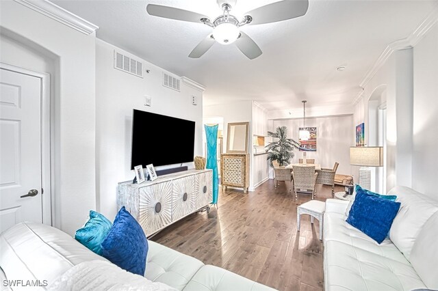 living room featuring ornamental molding, dark wood-type flooring, and ceiling fan