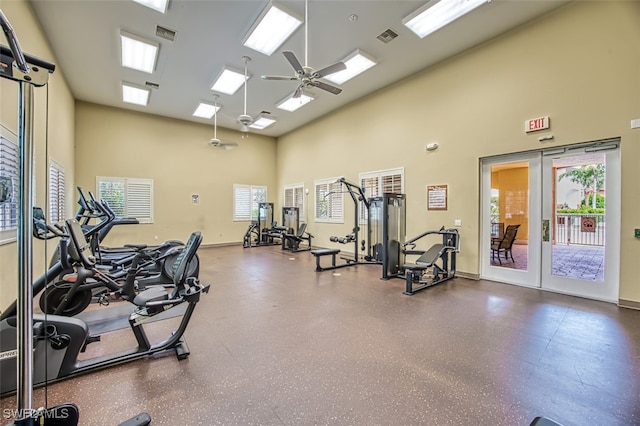 exercise room with a towering ceiling, ceiling fan, and french doors