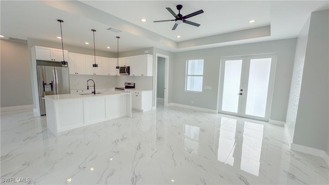 kitchen featuring sink, hanging light fixtures, a center island with sink, stainless steel appliances, and white cabinets