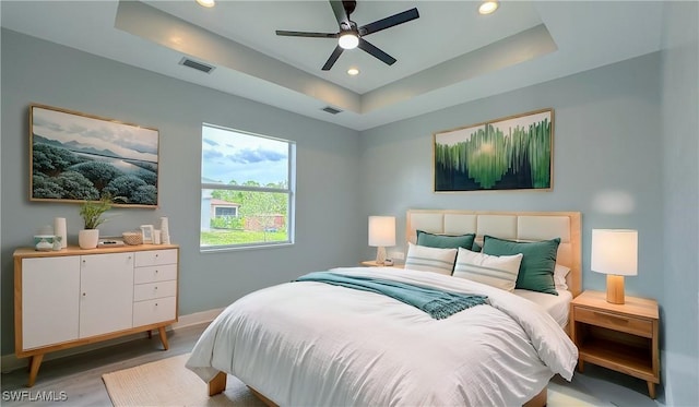 bedroom featuring a raised ceiling, ceiling fan, and light hardwood / wood-style floors