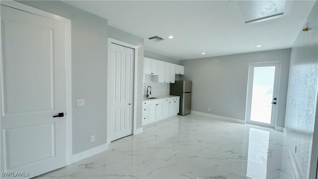 kitchen with white cabinetry, stainless steel fridge, and sink