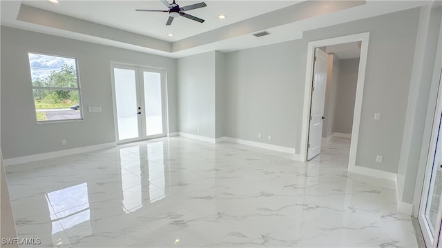 spare room featuring ceiling fan, a raised ceiling, and french doors