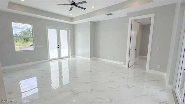 spare room with ceiling fan, french doors, and a raised ceiling