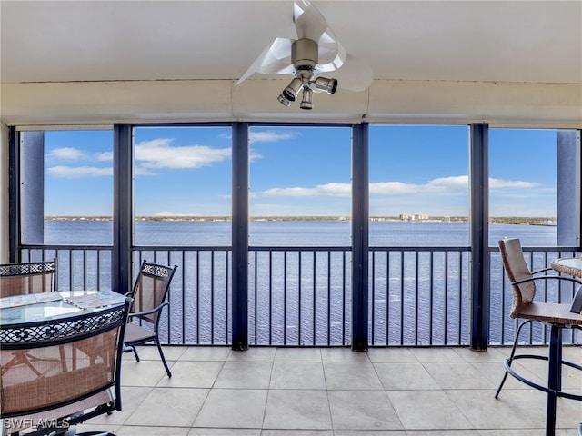 sunroom / solarium with ceiling fan and a water view