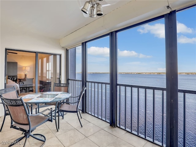 sunroom featuring a water view and ceiling fan