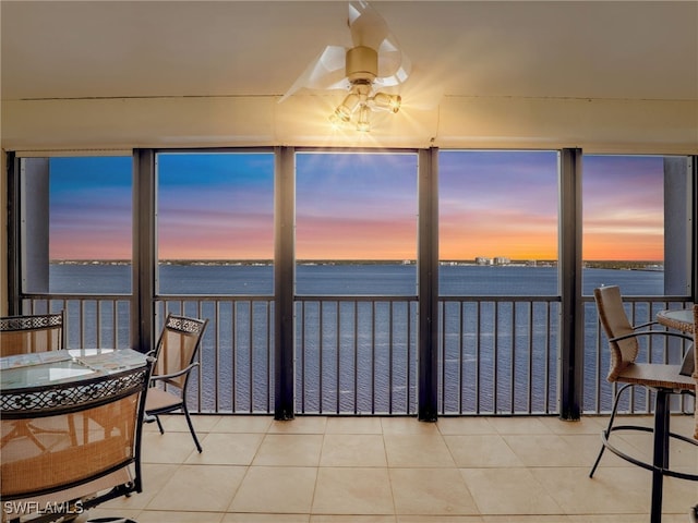 sunroom featuring a water view and ceiling fan