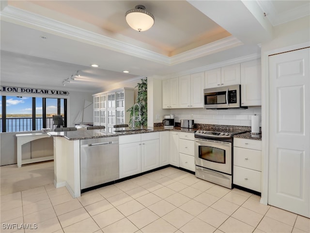 kitchen featuring sink, kitchen peninsula, appliances with stainless steel finishes, dark stone countertops, and white cabinets