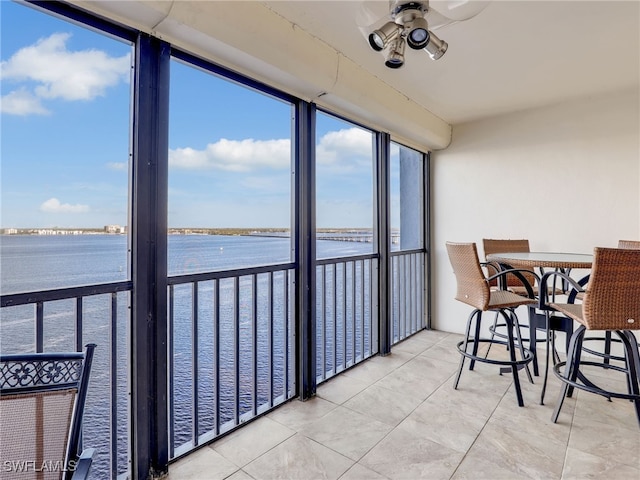 sunroom / solarium with ceiling fan and a water view