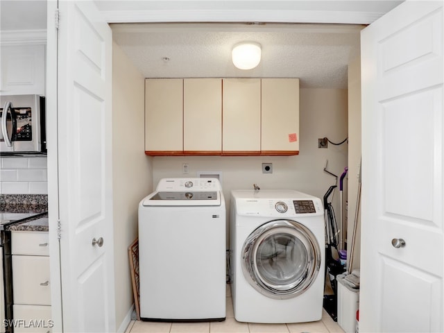 laundry room with a textured ceiling, cabinets, independent washer and dryer, and light tile patterned flooring