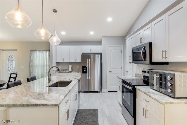 kitchen with hanging light fixtures, white cabinetry, a kitchen island with sink, and appliances with stainless steel finishes