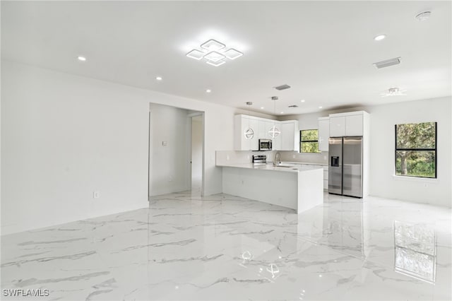 kitchen featuring kitchen peninsula, white cabinets, appliances with stainless steel finishes, pendant lighting, and sink