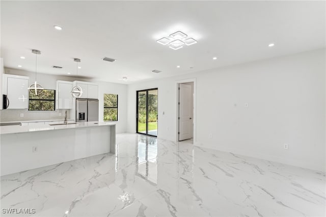 kitchen with sink, backsplash, hanging light fixtures, white cabinetry, and stainless steel fridge with ice dispenser