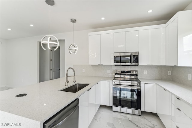 kitchen featuring white cabinetry, light stone countertops, sink, pendant lighting, and stainless steel appliances