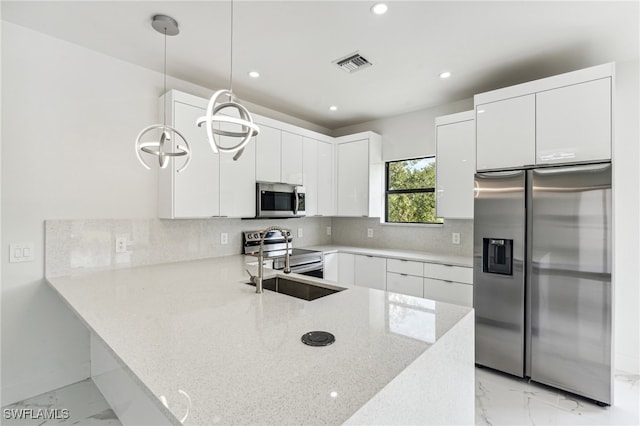 kitchen featuring light stone countertops, appliances with stainless steel finishes, kitchen peninsula, decorative light fixtures, and white cabinets