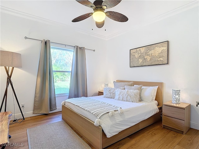 bedroom featuring crown molding, light wood-type flooring, and ceiling fan