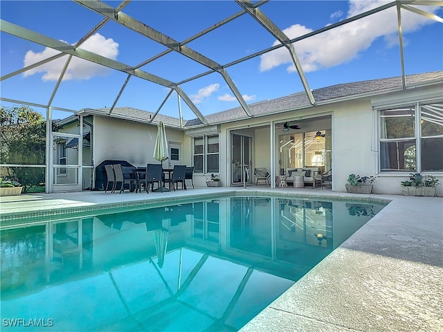 view of pool featuring a patio, glass enclosure, and ceiling fan