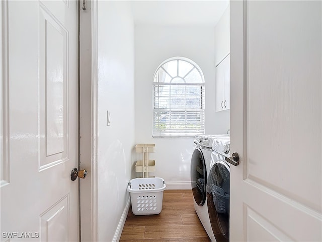 laundry room with cabinets, hardwood / wood-style floors, and washing machine and dryer