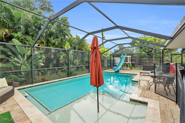 view of swimming pool featuring a patio, a water slide, and glass enclosure