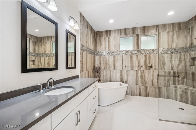 bathroom featuring tile patterned floors, vanity, independent shower and bath, and tile walls