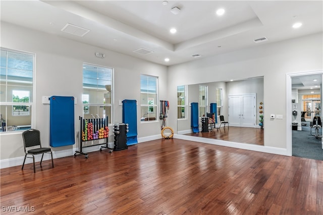 workout room with dark hardwood / wood-style floors and a raised ceiling