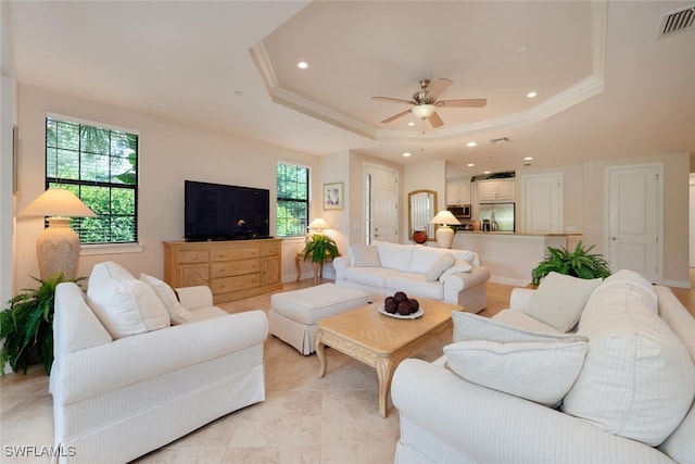 living room with crown molding, ceiling fan, plenty of natural light, and a raised ceiling