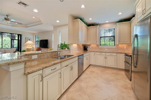 kitchen with sink, light stone countertops, stainless steel appliances, and a healthy amount of sunlight