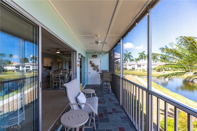 sunroom / solarium featuring a water view and ceiling fan