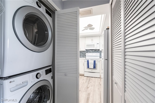 laundry room featuring stacked washer / dryer and light hardwood / wood-style flooring