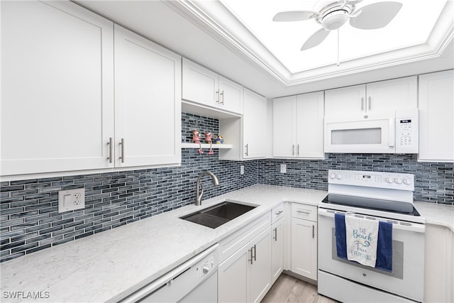 kitchen featuring tasteful backsplash, white cabinetry, a tray ceiling, sink, and white appliances