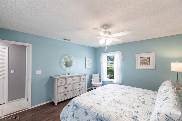 bedroom with ceiling fan, a textured ceiling, and dark hardwood / wood-style floors