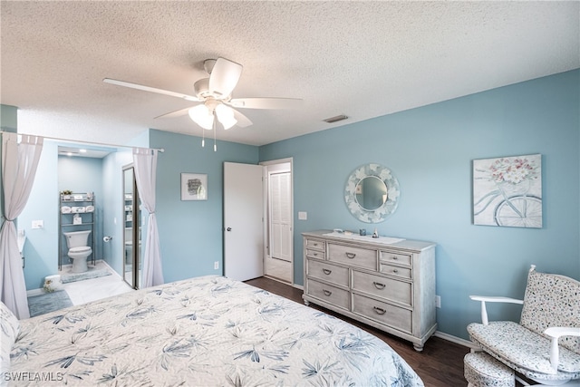 bedroom featuring dark hardwood / wood-style floors, a textured ceiling, connected bathroom, and ceiling fan