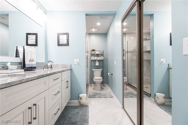 bathroom with toilet, a shower with shower door, a textured ceiling, and vanity