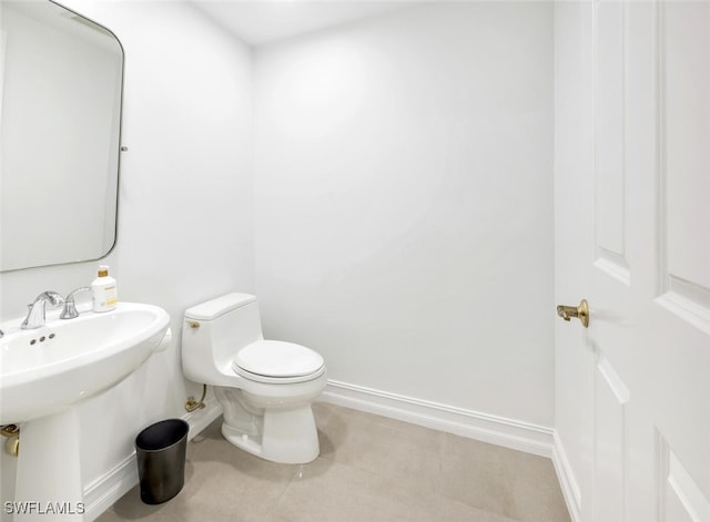 half bathroom featuring a sink, baseboards, and toilet