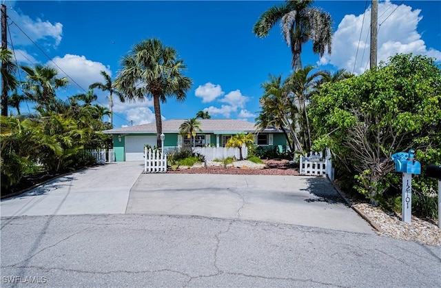 single story home featuring a fenced front yard, an attached garage, and driveway