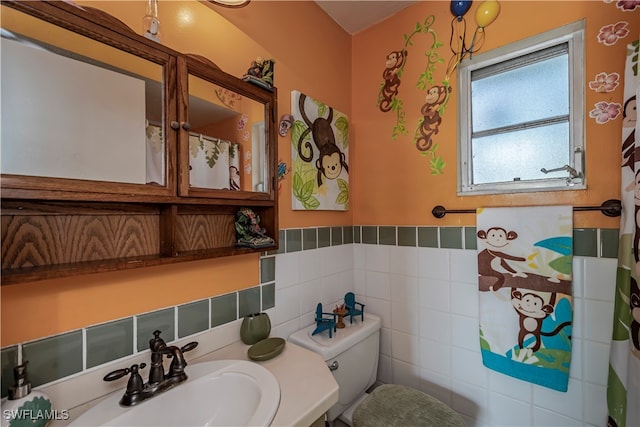 bathroom with toilet, tile walls, and sink