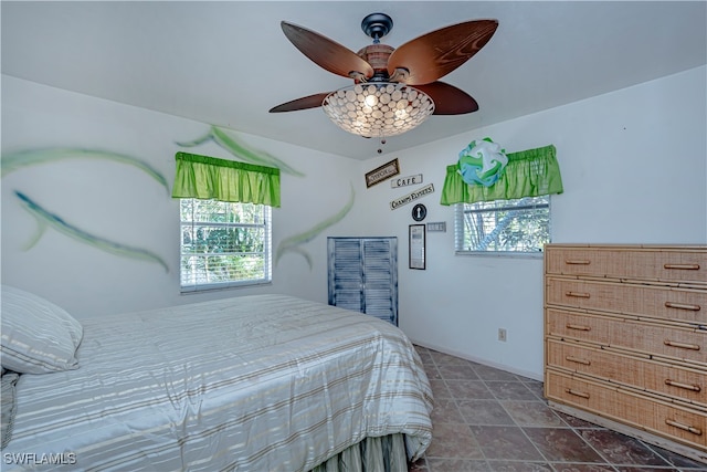 bedroom featuring multiple windows, ceiling fan, and dark tile patterned floors