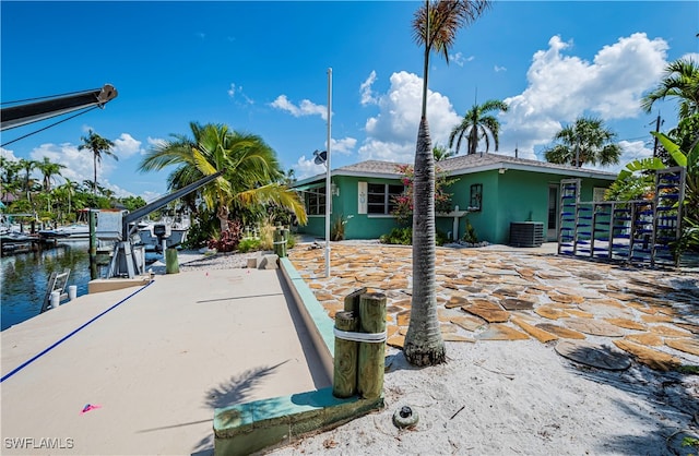 view of front of property with central AC, a dock, a water view, and a patio