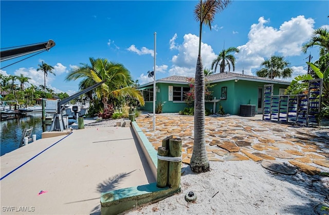 exterior space featuring boat lift, central air condition unit, stucco siding, and a water view