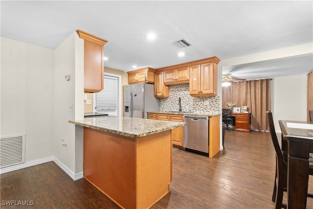 kitchen featuring light stone countertops, dark hardwood / wood-style flooring, kitchen peninsula, ceiling fan, and stainless steel appliances