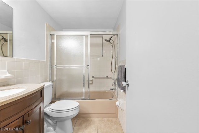 full bathroom with tile walls, shower / bath combination with glass door, toilet, vanity, and tile patterned floors