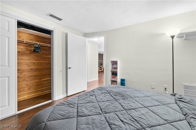 bedroom with a closet, hardwood / wood-style flooring, and wooden walls