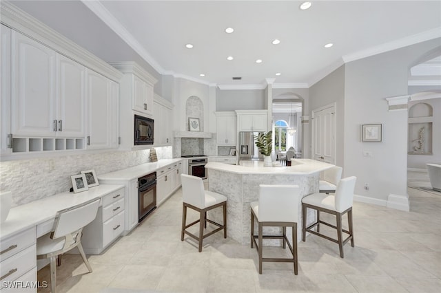 kitchen featuring black appliances, a kitchen bar, a kitchen island, white cabinetry, and tasteful backsplash