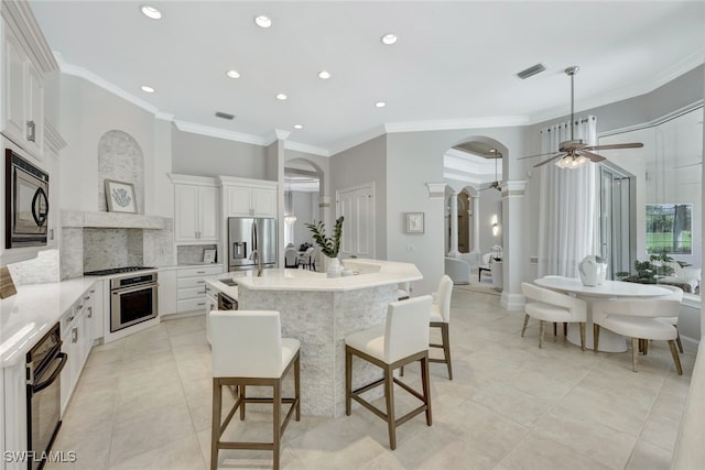 kitchen with a large island, black appliances, white cabinets, decorative light fixtures, and tasteful backsplash