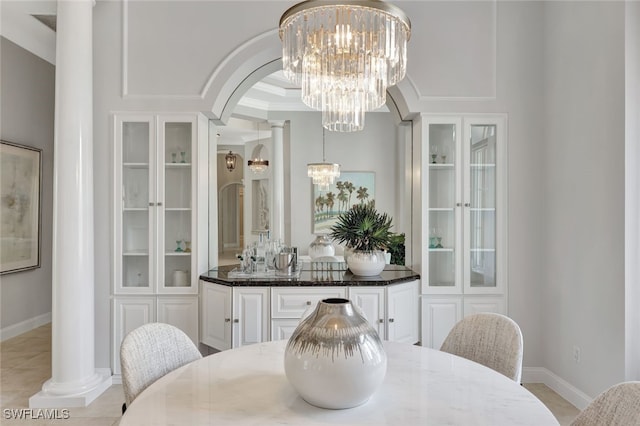 dining area with ornate columns, light tile patterned flooring, an inviting chandelier, and crown molding