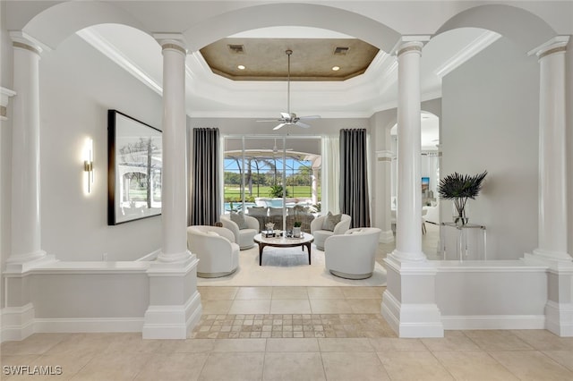 living room with crown molding, ceiling fan, a tray ceiling, and light tile patterned floors