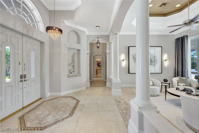 tiled foyer entrance featuring ceiling fan with notable chandelier, ornamental molding, a tray ceiling, and ornate columns