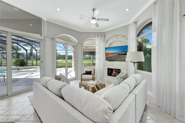 living room featuring a fireplace, ceiling fan, a wealth of natural light, and ornamental molding